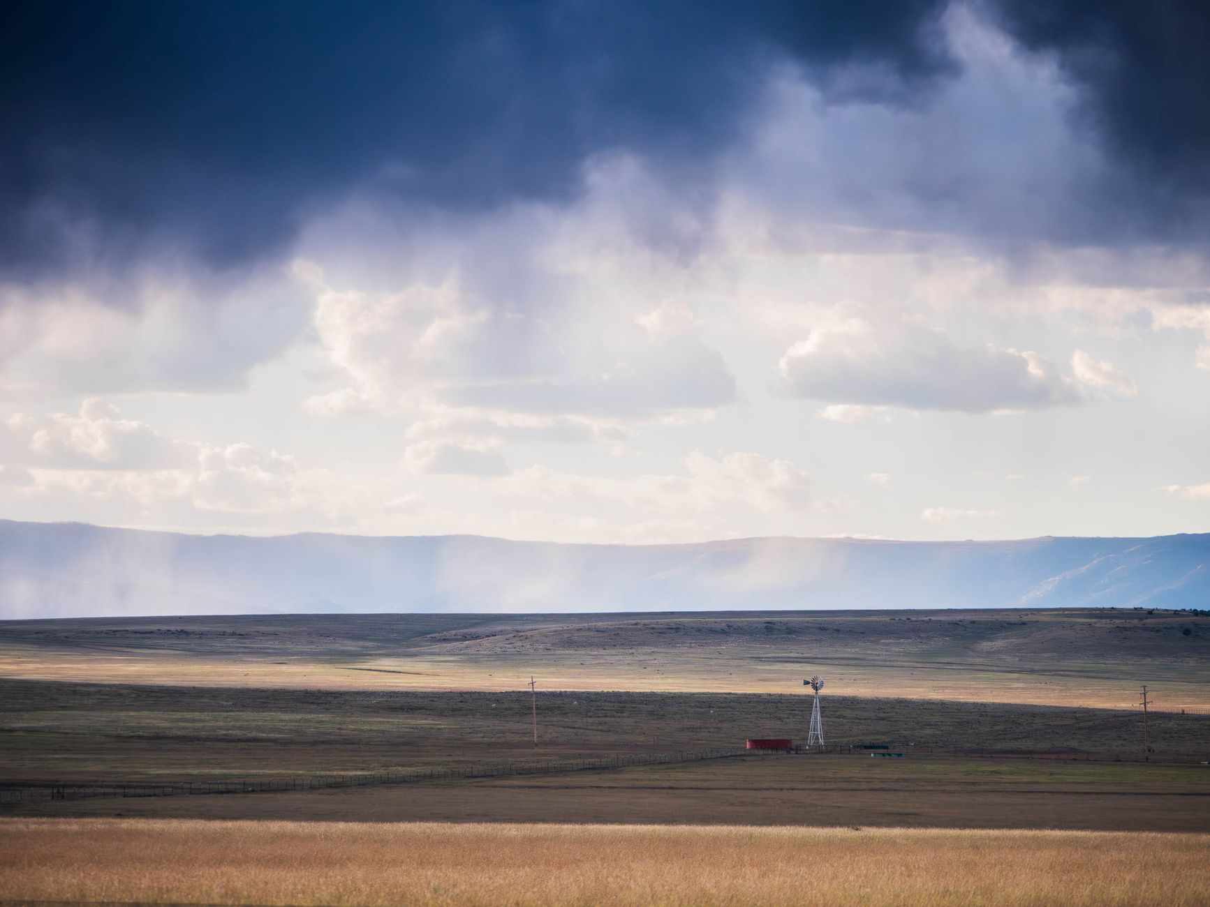 Rural New Mexico high-desert rangeland and mesa landscape, golden-hour light.
